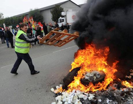 Un manifestante arroja un palé a una barricada en llamas EFE