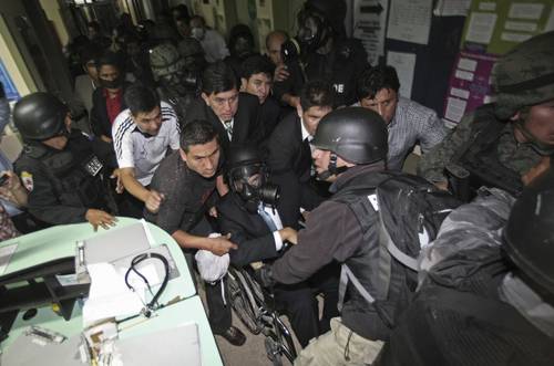 En silla de ruedas y con máscara antigás el presidente de Ecuador, Rafael Correa, es sacado por el ejército del Hospital de la Policía donde fue secuestrado el 30 de septiembre, día de la sublevación de uniformados