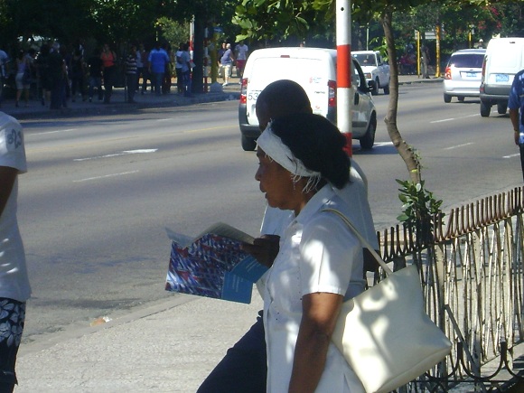Cubanos leen folletos con Lineamientos para el desarrollo económico y social del Partido y la Revolución en la Habana, Cuba 